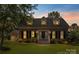 Charming brick home at dusk featuring a landscaped front yard and dormer windows at 1208 Chausley Ct, Charlotte, NC 28211