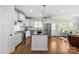 Modern kitchen with island, white cabinetry, stainless appliances, and access to living room at 1241 Rollins Ave, Charlotte, NC 28205