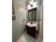 Cozy half-bathroom featuring a light-green paint, decorative mirror, and vanity with dark cabinets at 12610 Angel Oak Dr, Huntersville, NC 28078