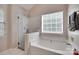 A relaxing bathroom boasts a glass enclosed shower and soaking tub, illuminated by natural light at 12719 Vantage Point Ln, Huntersville, NC 28078
