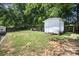 Backyard featuring a shed, lawn, mature trees, and partial fence at 131 Swink Sw St, Concord, NC 28027