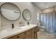Bright bathroom featuring a double vanity, round mirrors, and a toilet with a patterned shower curtain at 141 Ole Eastpointe Dr, York, SC 29745