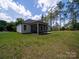 Backyard view featuring a screened porch, green lawn, and mature trees offering shade and privacy at 142 Highland Dr, New London, NC 28127