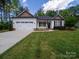 Inviting single-story home featuring an attached garage, beautiful landscaping, and green lawn at 142 Highland Dr, New London, NC 28127
