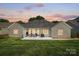 Beautiful dusk image of the home's back exterior, showing a covered patio, an open patio, and a large backyard at 146 Burtons Barn Rd, Mooresville, NC 28115