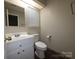 This bathroom features a single sink vanity, mirror, toilet, and dark floor at 2105 Killarney Pl, Charlotte, NC 28262