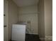 This is a laundry room with a washing machine, overhead storage shelf, and dark floor at 2105 Killarney Pl, Charlotte, NC 28262
