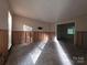 This living room is gutted, showing studs, damaged walls, and flooring, with natural light streaming in at 2105 Killarney Pl, Charlotte, NC 28262