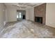 Open living room space with exposed flooring, brick fireplace, and doorway to the kitchen, offering renovation potential at 2105 Killarney Pl, Charlotte, NC 28262