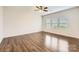 Spacious bedroom featuring wood-look flooring, ceiling fan, and natural light from three windows at 2327 Glenway Trail Ct, Pineville, NC 28134