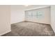 Well-lit empty bedroom with plush carpeting and three windows allowing for lots of natural light at 2327 Glenway Trail Ct, Pineville, NC 28134