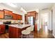 Virtual staged kitchen with cherry cabinets, a large island, stainless steel appliances, and light-filled dining area at 2327 Glenway Trail Ct, Pineville, NC 28134