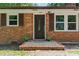 Close-up of front entrance with a dark door, brick facade, and decorative plants at 2401 Woodleaf Dr, Gastonia, NC 28052
