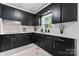Charming kitchen featuring black cabinets, light quartz countertops and modern faucet against a large window at 2401 Woodleaf Dr, Gastonia, NC 28052