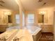 Bright bathroom features a soaking tub, double vanity, and a large mirror at 318 Linsbury Ct, Gastonia, NC 28056
