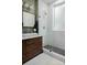 Bathroom with white subway tile shower, wood vanity, and patterned wallpaper at 324 N 5Th St, Albemarle, NC 28001