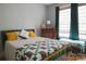 Bright bedroom with a patterned quilt, yellow throw pillows, and a dresser at 324 N 5Th St, Albemarle, NC 28001
