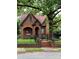 Charming brick home with a unique roof, arched entryway, black iron fence, and lush landscaping at 324 N 5Th St, Albemarle, NC 28001