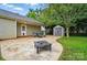 Paver patio with a fire pit, seating, black fence, storage shed, and access to the house at 42 Linford St, Belmont, NC 28012