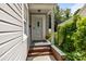 The front entrance has brick steps, gray siding, a gray front door and decorative plants at 509 W Sixth Ave, Gastonia, NC 28052