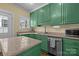 Granite countertops complement green kitchen cabinets with wooden floors and stainless steel dishwasher at 509 W Sixth Ave, Gastonia, NC 28052