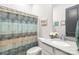 Bathroom with a single sink vanity, neutral stone countertop, and colorful patterned shower curtain at 5210 Kelly St, Charlotte, NC 28205