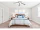 Bright bedroom featuring a bed with blue pillows, three windows, and neutral carpet at 5210 Kelly St, Charlotte, NC 28205