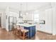 Spacious kitchen featuring white cabinetry, stainless appliances, a blue island, and wood flooring at 5210 Kelly St, Charlotte, NC 28205