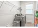 Functional laundry room with modern washer and dryer, shelving, and a bright window at 5210 Kelly St, Charlotte, NC 28205