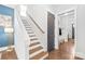 Bright, modern staircase featuring hardwood steps, white risers and walls, and a dark gray door at 5210 Kelly St, Charlotte, NC 28205