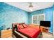 Cozy bedroom features vibrant blue walls, ceiling fan, and bright natural light from the large window at 5238 Downing Creek Dr, Charlotte, NC 28269