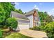 Attractive side view of home with brick and blue siding, well-kept lawn, mature tree, and a two-car garage at 5238 Downing Creek Dr, Charlotte, NC 28269