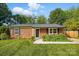 Charming brick home featuring a well-manicured lawn, mature trees, and a black front door at 529 Dedmon Dr, Charlotte, NC 28216