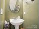Half bathroom featuring a pedestal sink, decorative mirror, and updated fixtures at 541 River Park Rd, Belmont, NC 28012