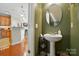 Half bathroom with pedestal sink, decorative shelves, and easy access to kitchen and dining at 541 River Park Rd, Belmont, NC 28012