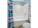Bathroom featuring tub with shower, toilet, blue paint and a beach-themed painting on the wall at 541 River Park Rd, Belmont, NC 28012