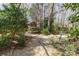 A tranquil gravel pathway leads through a lush backyard, featuring a whimsical garden gnome statue at 5550 Monticello Nw Dr, Concord, NC 28027