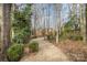 Gravel pathway winds through a backyard, bordered by lush greenery and leading to a wooden pergola at 5550 Monticello Nw Dr, Concord, NC 28027