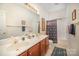 Bright bathroom with dual sinks, wood cabinets, and tub/shower at 5550 Monticello Nw Dr, Concord, NC 28027