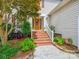 Inviting home entrance with a beautiful wood door, brick steps, and manicured landscaping at 5716 Trimmings Ct, Charlotte, NC 28226