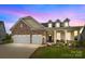 Charming single-Gathering home showcasing a stone facade, two-car garage, and inviting front porch area at dusk at 7010 Brush Crk, Monroe, NC 28110