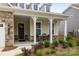 Inviting front porch features stone accents, white pillars, and cozy seating, enhancing the home's curb appeal at 7010 Brush Crk, Monroe, NC 28110