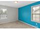 Bright bedroom featuring neutral carpet flooring, blue accent wall, and windows with coverings at 8347 Dallas Bay Rd, Charlotte, NC 28278