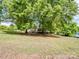 A large yard with mature trees offers a shaded view of a home with a charming front porch at 84 Sumner Nw Ave, Concord, NC 28027