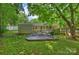 Exterior backyard view with a patio set, grill, green grass, mature trees, and single story home at 901 Scaleybark Rd, Charlotte, NC 28209