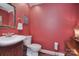 Compact powder room featuring red walls, decorative mirror, and wood vanity with matching toilet at 9625 Surface Hill Rd, Mint Hill, NC 28227