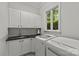 Functional laundry room with modern appliances, sink, and storage cabinets at 9831 Sedgefield Dr, Waxhaw, NC 28173