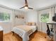 Bright bedroom with hardwood floors, two windows, a ceiling fan, and colorful wall art at 1031 Eldorado Ave, Charlotte, NC 28262