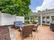 Relaxing outdoor patio with brick flooring, wicker furniture, and view to a white fence at 1031 Eldorado Ave, Charlotte, NC 28262