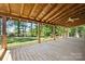 Spacious back porch with wood flooring and ceiling with view of the green backyard and wooded area at 11227 Cool Springs Rd, Cleveland, NC 27013